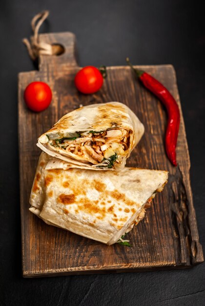 Burrito wraps with chicken and vegetables on a cutting board, against a background of concrete, Mexican shawarma