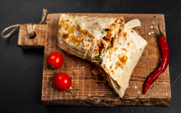 Burrito wraps with chicken and vegetables on a cutting board, against a background of concrete, Mexican shawarma