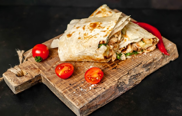 Burrito wraps with chicken and vegetables on a cutting board, against a background of concrete, Mexican shawarma