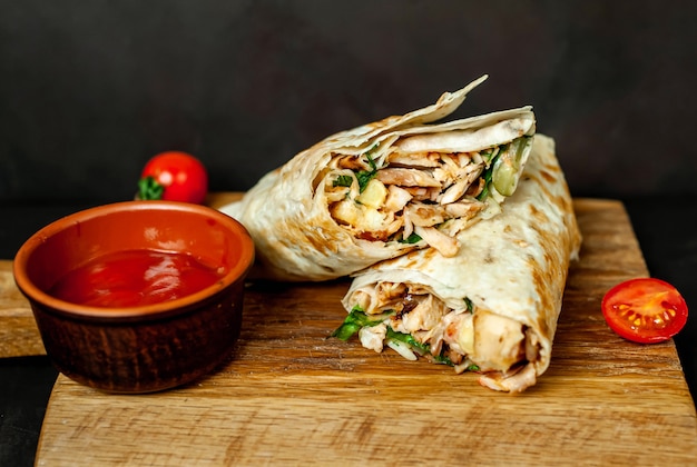 Burrito wraps with chicken and vegetables on a cutting board, against a background of concrete, Mexican shawarma