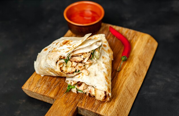 Burrito wraps with chicken and vegetables on a cutting board, against a background of concrete, Mexican shawarma