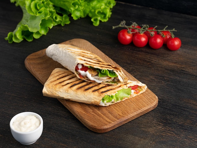 Burrito wraps with chicken and vegetables on a cutting board against a background of concrete Mexican shawarma