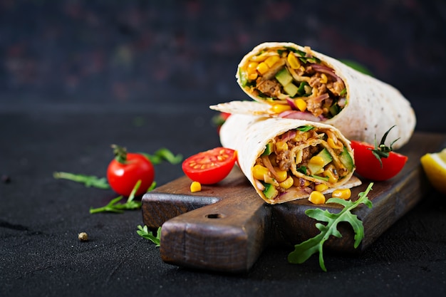 Burritos wraps with beef and vegetables on  black background. Beef burrito, mexican food.