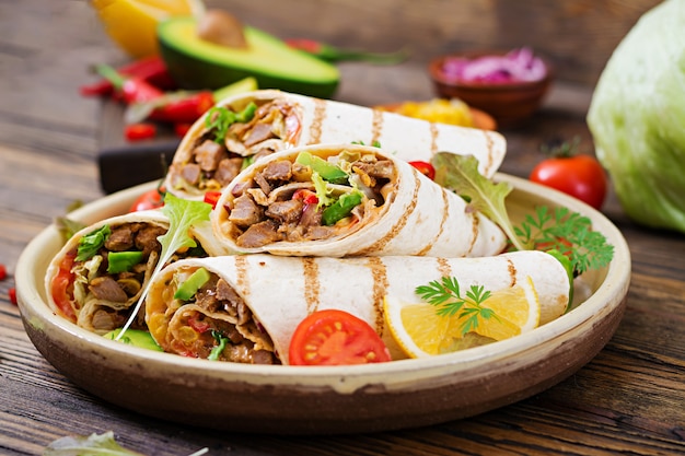 Burritos wraps with beef and vegetables on a wooden table. Beef burrito , mexican food. Mexican cuisine.