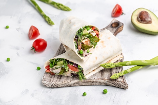 Burritos wraps with chicken and vegetables asparagus, avocado, tomatoes, peas, cheese