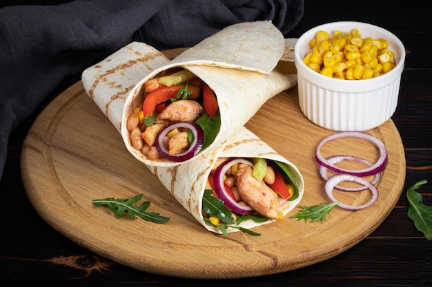 Burritos wraps with chicken and vegetables on dark background. Mexican food.