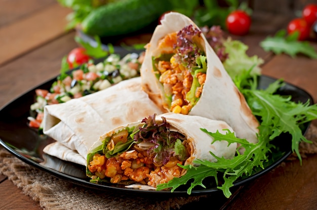 Burritos wraps with minced beef and vegetables on a wooden background