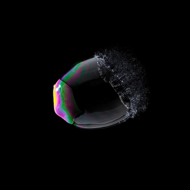 Burst soap bubble in colorful colors on black background