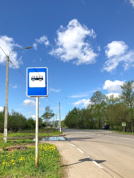 Bus stop traffic sign against blue sky at the road edge