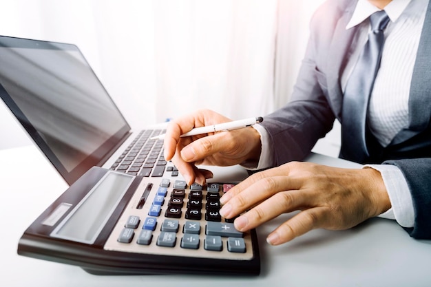 Business accounting concept Business man using calculator with computer laptop budget and loan paper in office