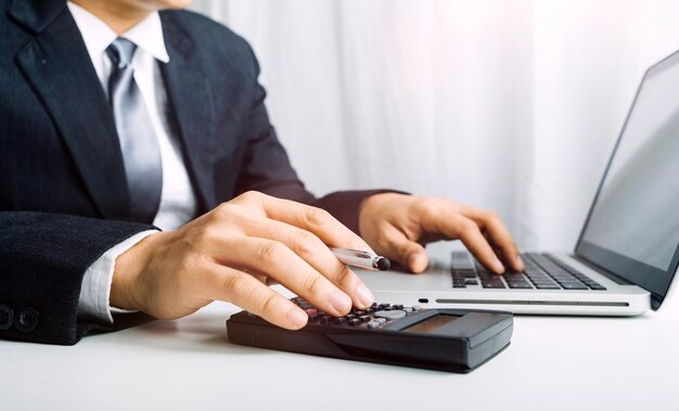 Business accounting concept Business man using calculator with computer laptop budget and loan paper in office