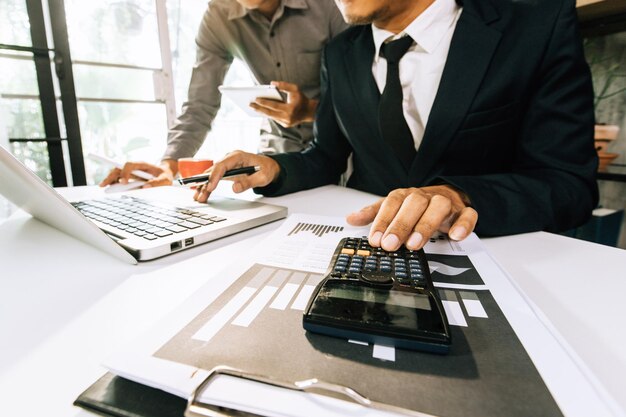 Business accounting concept business man using calculator with\
computer laptop budget and loan paper in office