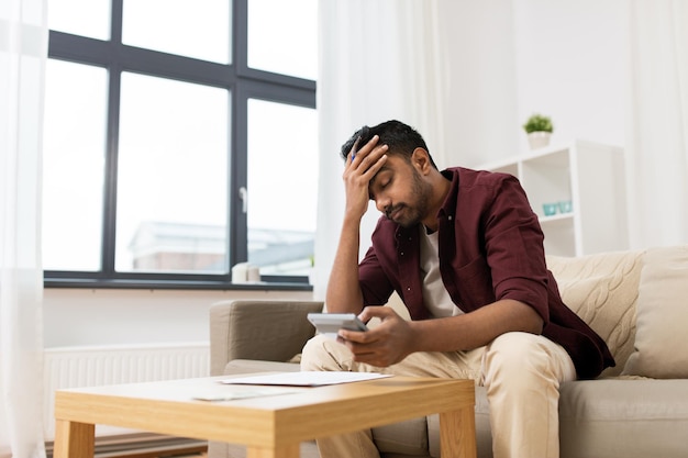 Photo business accounting finances and people concept upset man with papers and calculator at home