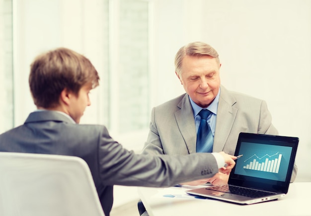 business, advertisement, technology and office concept - older man and young man with laptop computer in office