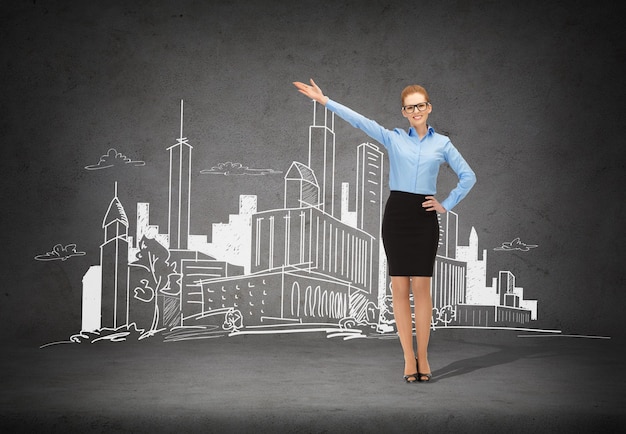 business, advertising and office concept - smiling businesswoman in eyeglasses pointing her hand