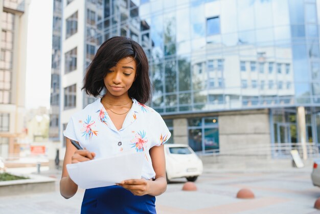 Business afro american woman holding files near office