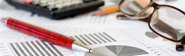 Business analytics, graphs and charts. A schematic drawing on paper. Ballpoint pen, glasses and calculator