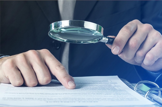 Business analytics and statistics. Businessman with report using a magnifying glass.