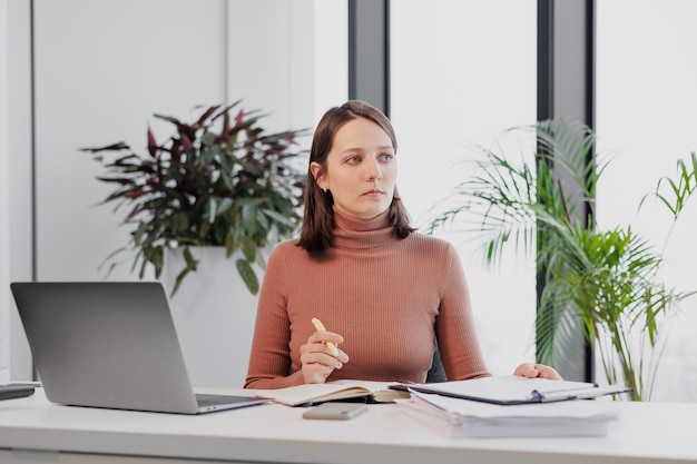 Фото Бизнес и финансы женщина-предприниматель в офисе работает с ноутбуком успешная европейская женщина-финансист-маркетолог проверяет счетчик