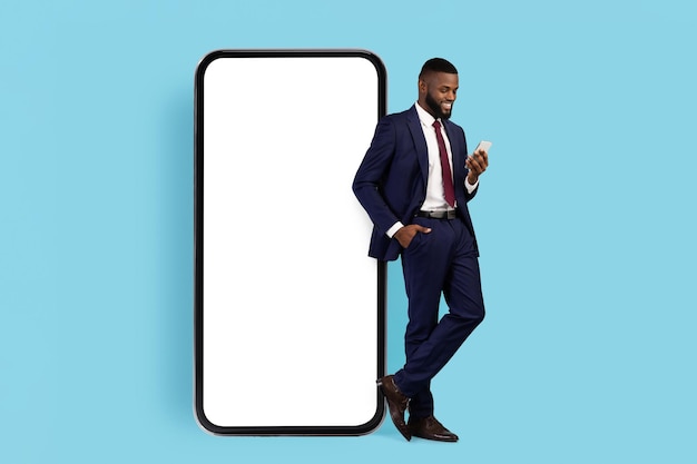 Business app black businessman in suit standing next to big blank cellphone