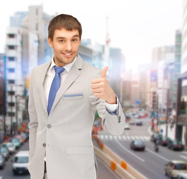 business, architecture and building concept - handsome businessman showing thumbs up