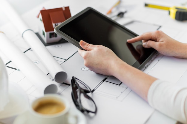 business, architecture, building, construction and people concept - close up of architect hand with living house blueprint and tablet pc computer