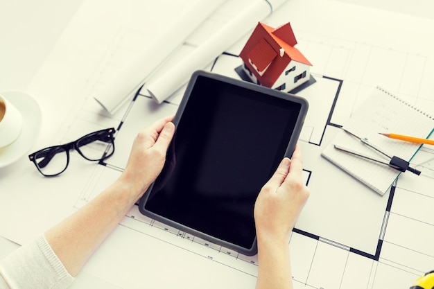 business, architecture, building, construction and people concept - close up of architect hand with living house blueprint and tablet pc computer