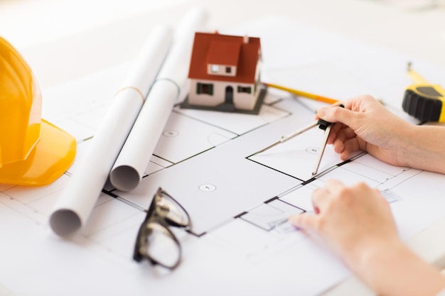 business, architecture, building, construction and people concept - close up of architect hands with compass measuring living house blueprint