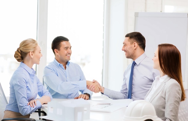 business, architecture and office concept - happy team of architects and designers in office shaking hands