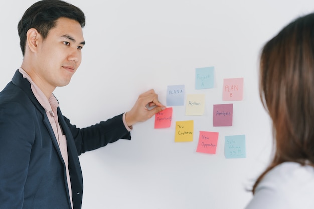 Foto due persone asiatiche che si incontrano in ufficio e usano le note di post-it per condividere l'idea