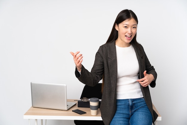 Business asian woman in her workplace isolated on making guitar gesture