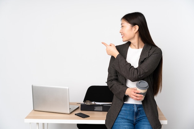 Business asian woman in her workplace isolated on pointing back with the index finger