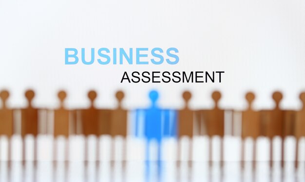 Business assessment sign above line of toy human figures
