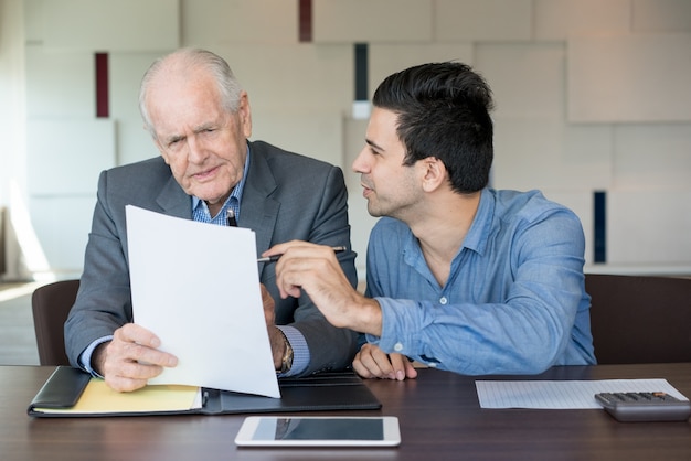 Business assistant showing papers to boss