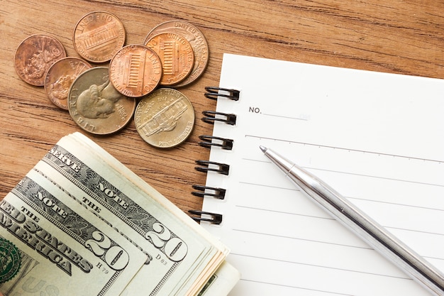 business background. pen on empty notebook with us dollar bills and black coffee. 