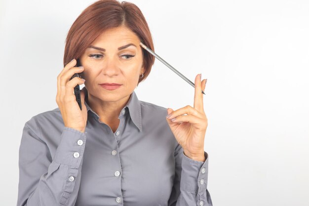 Business beautiful woman speaks on the phone with a pencil in her hand