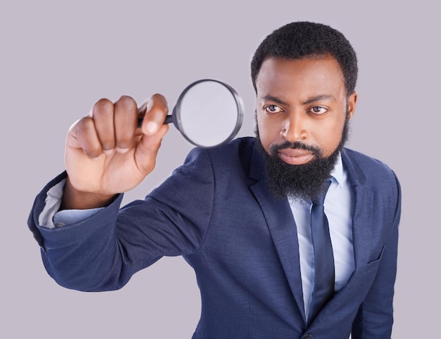 Business black man magnifying glass and studio with focus for quality inspection compliance and stop fraud Businessman inspector and auditor at company with attention for financial health at job