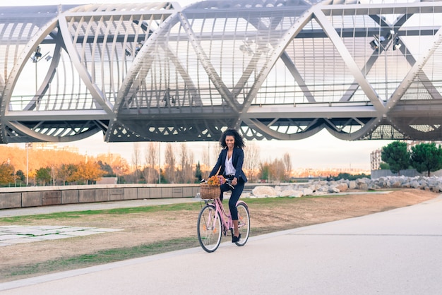 Business black woman riding a vintage bicycle in the city