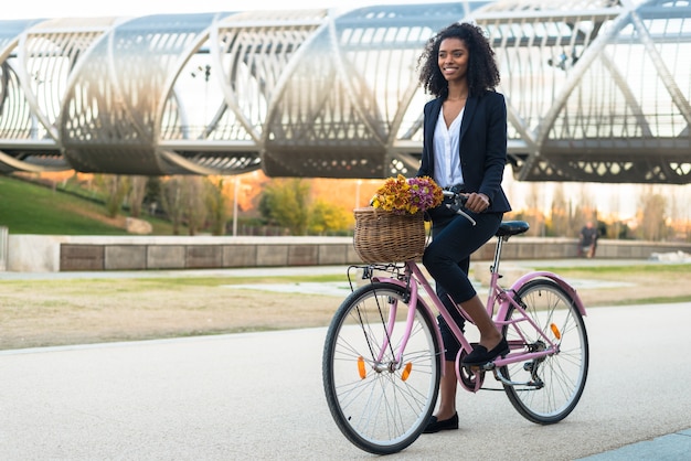 Business black woman riding a vintage bicycle in the city