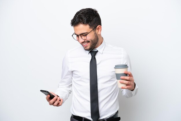 Business Brazilian man isolated on white background holding coffee to take away and a mobile