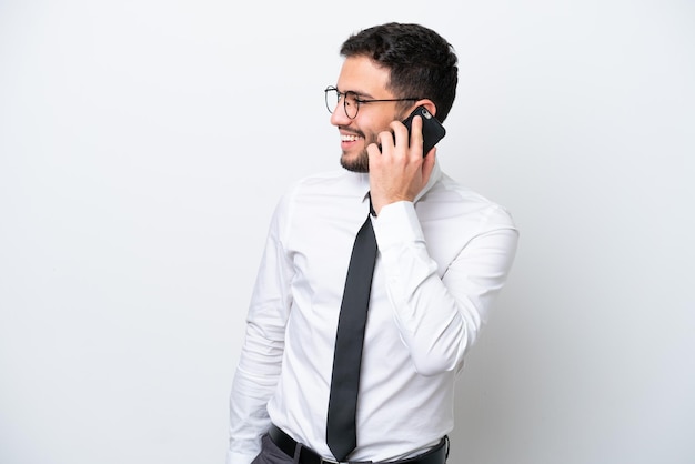 Business Brazilian man isolated on white background keeping a conversation with the mobile phone with someone