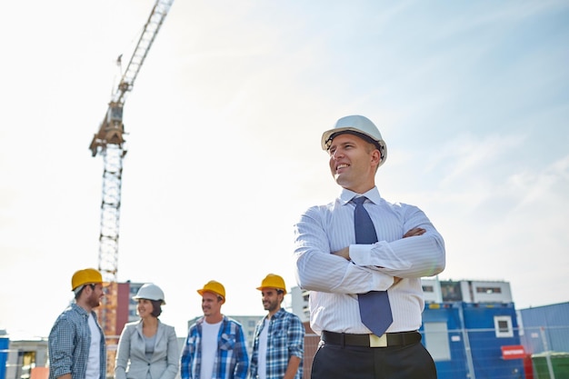 business, building, teamwork en people concept - groep lachende bouwers en architect in veiligheidshelmen op de bouwplaats