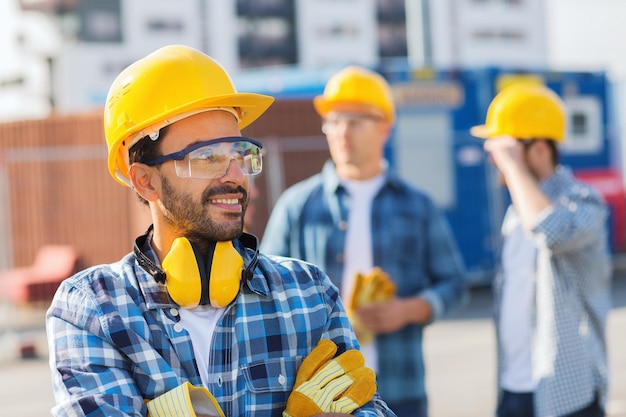 business, building, teamwork en people concept - groep lachende bouwers in hardhats buitenshuis