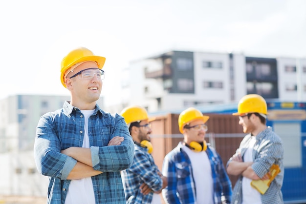 business, building, teamwork en people concept - groep lachende bouwers in hardhats buitenshuis