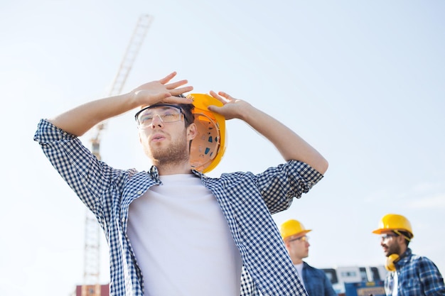 business, building, teamwork and people concept - group of builders in hardhats outdoors