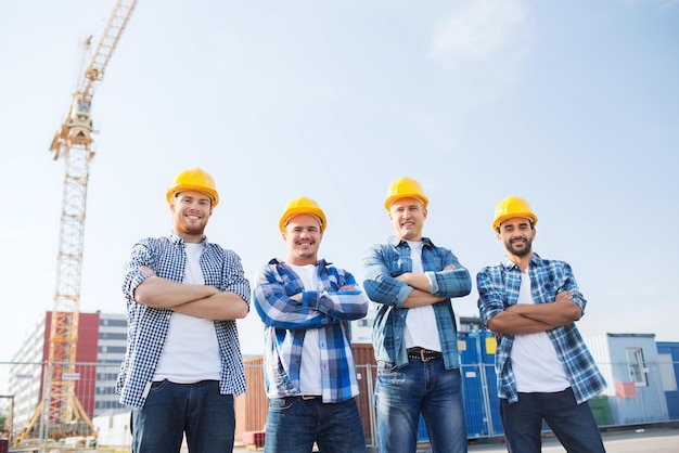 business, building, teamwork and people concept - group of smiling builders in hardhats outdoors