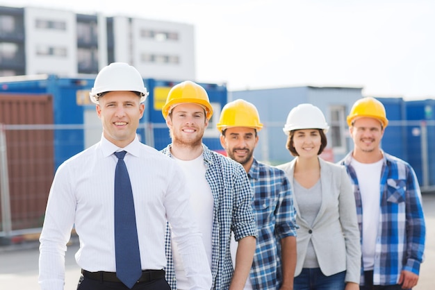 business, building, teamwork and people concept - group of smiling builders in hardhats outdoors