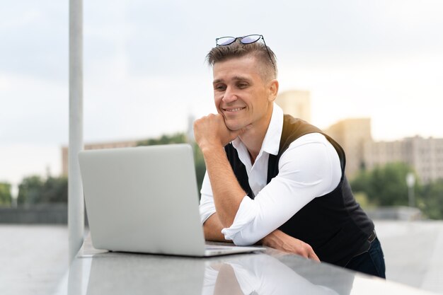 Business. Businessman Using Laptop Outdoor Adult Caucasian Male Business Person Eyeglesses Watching notebook Screen Outside Smiling Sulnlight Background Big City Street