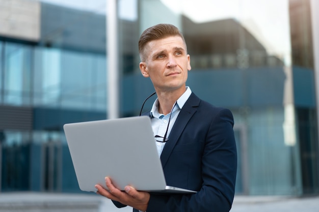 Business. Businessman Using Laptop Outdoors. Serious Pensive Caucasian Male Eyeglasses Business Person Computer Outside Modern Technology Concept Young Adult Manager Crisis Thinking Trouble Idea