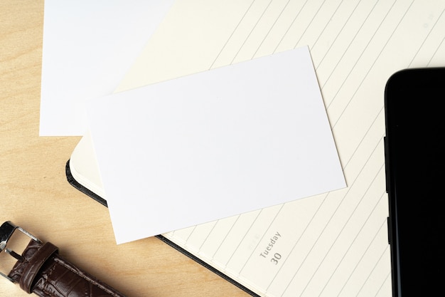 Photo business card and open notepad on office table close up